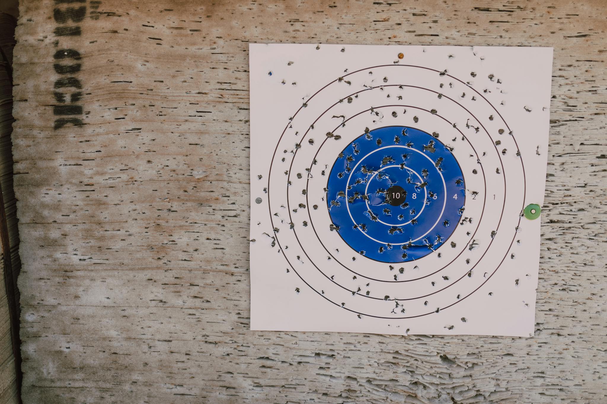 Close-up of a well-used archery target with numerous bullet holes in an outdoor setting.