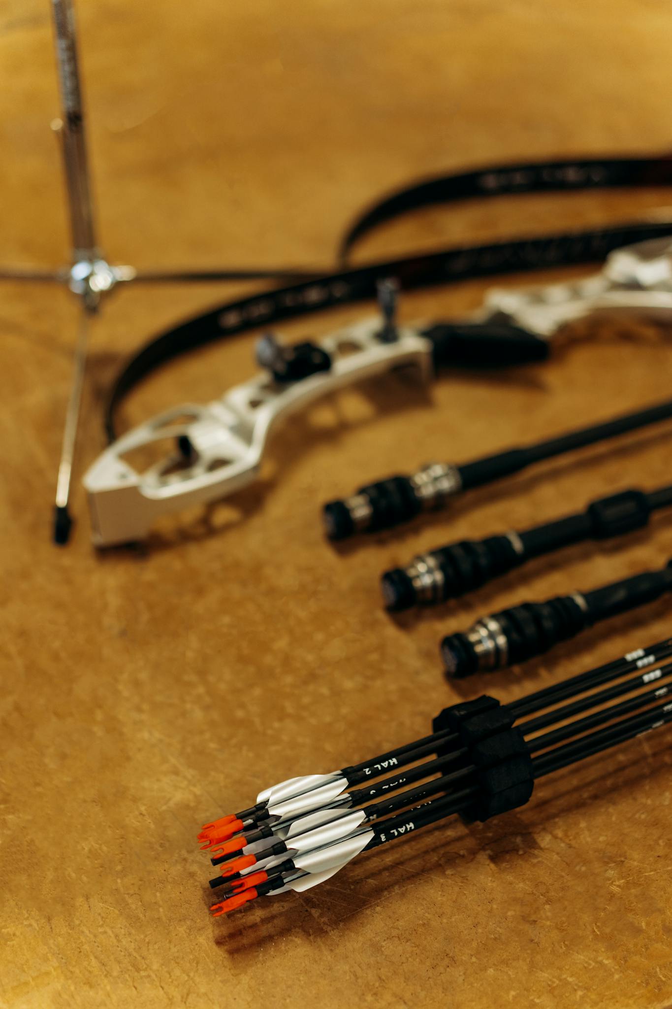 Close-up of archery equipment including a bow and arrows on a wooden surface.