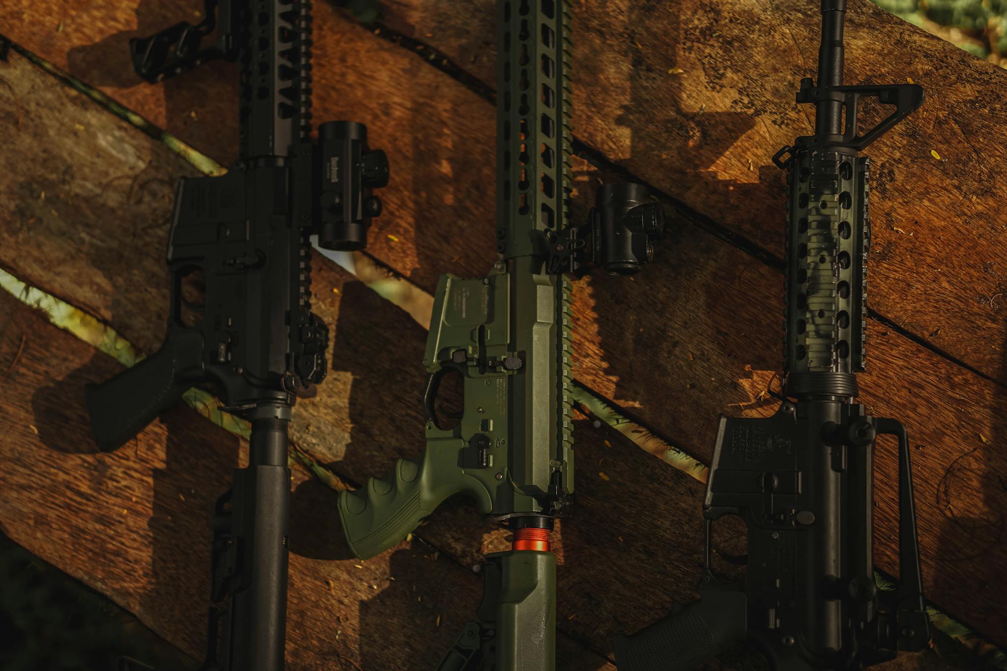 Three rifles laid on a rustic wooden surface, captured with natural lighting.